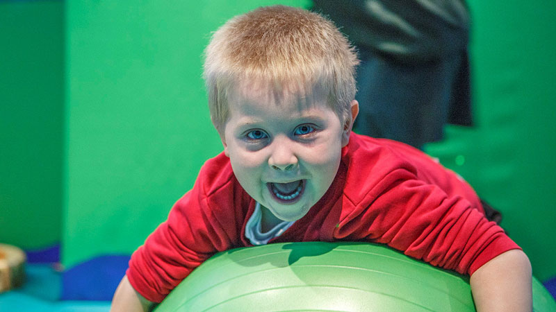 Happy boy playing with large green ball