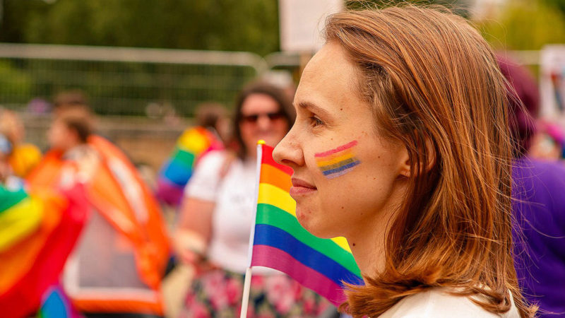 Smiling young woman with a rainbow painted on her cheek