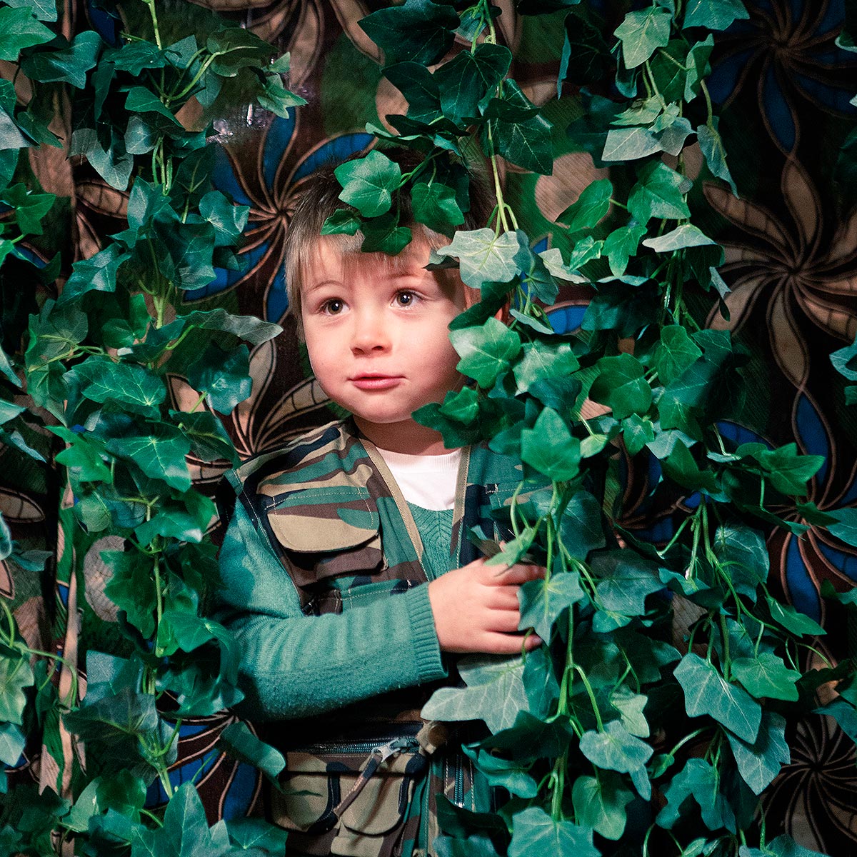 Young boy peeping out through leaves